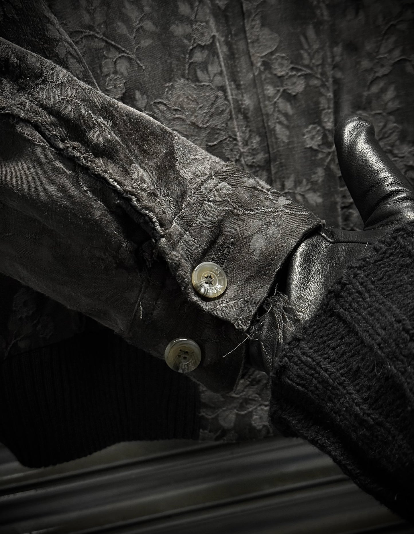 Close-up of a textured fabric surface with buttons and leather elements.