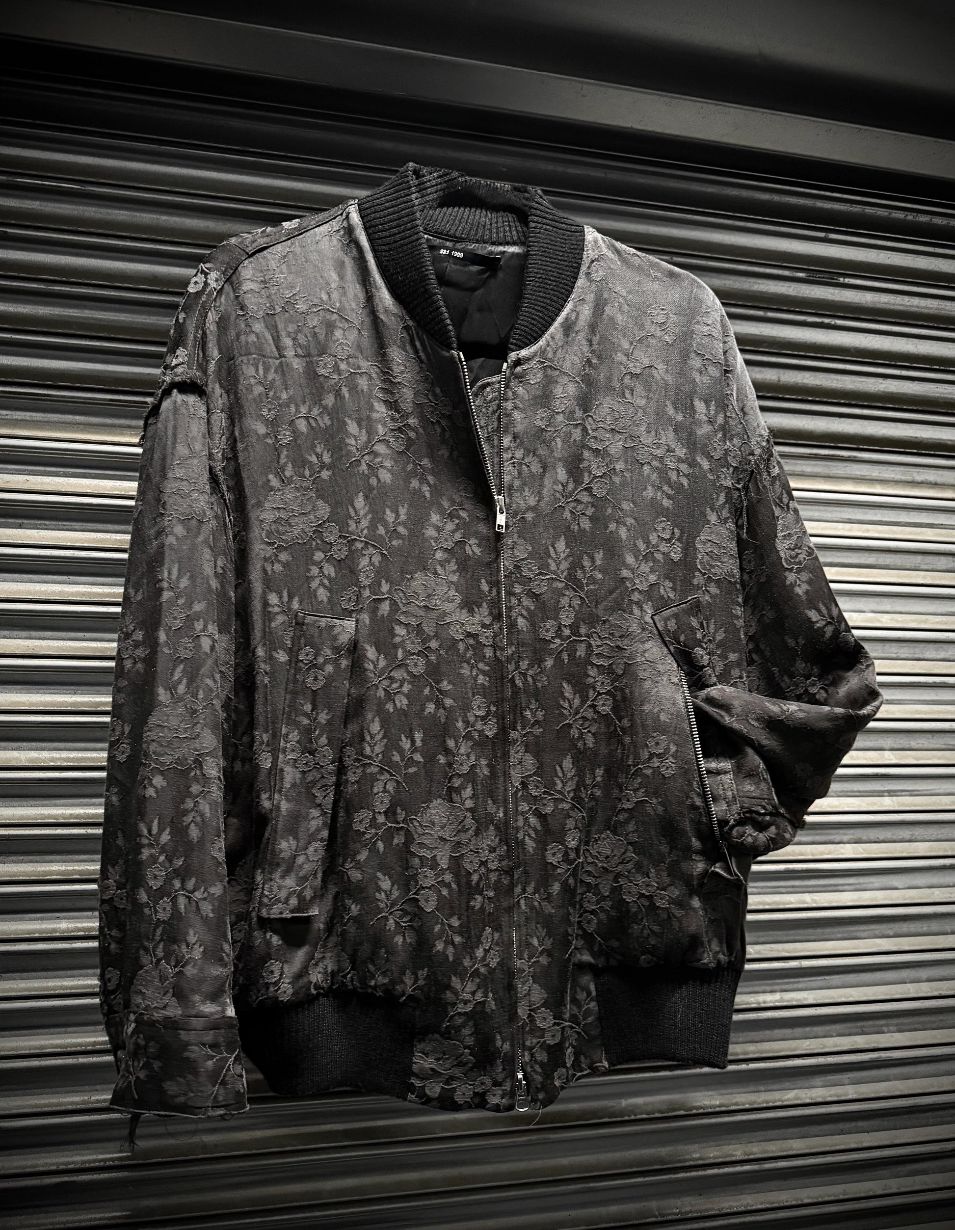 Floral-patterned jacket hanging against a corrugated metal background