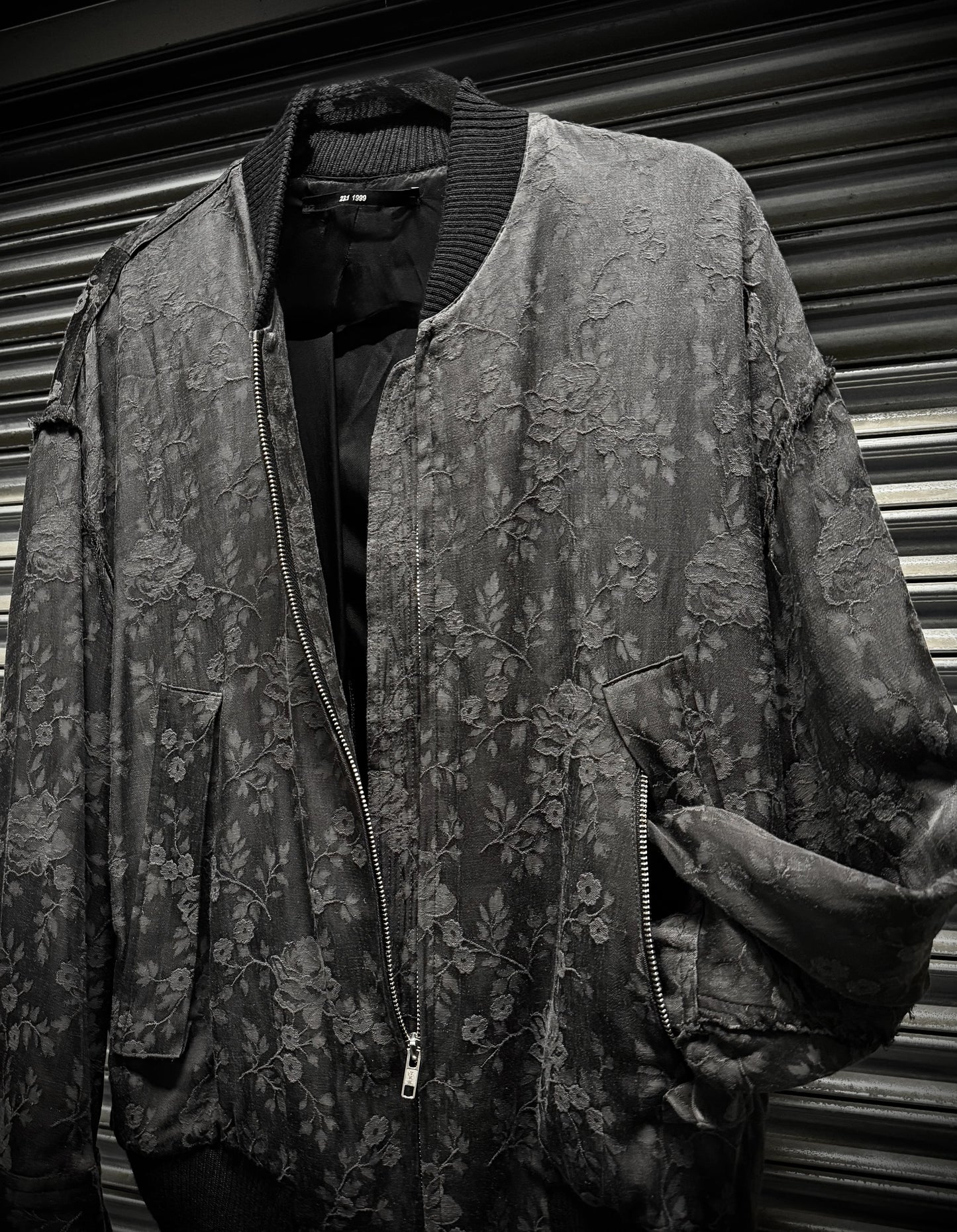Floral patterned jacket on a mannequin against a corrugated metal background