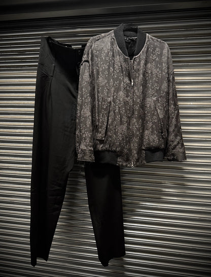 Two jackets, one black and one patterned, hanging against a corrugated metal background.