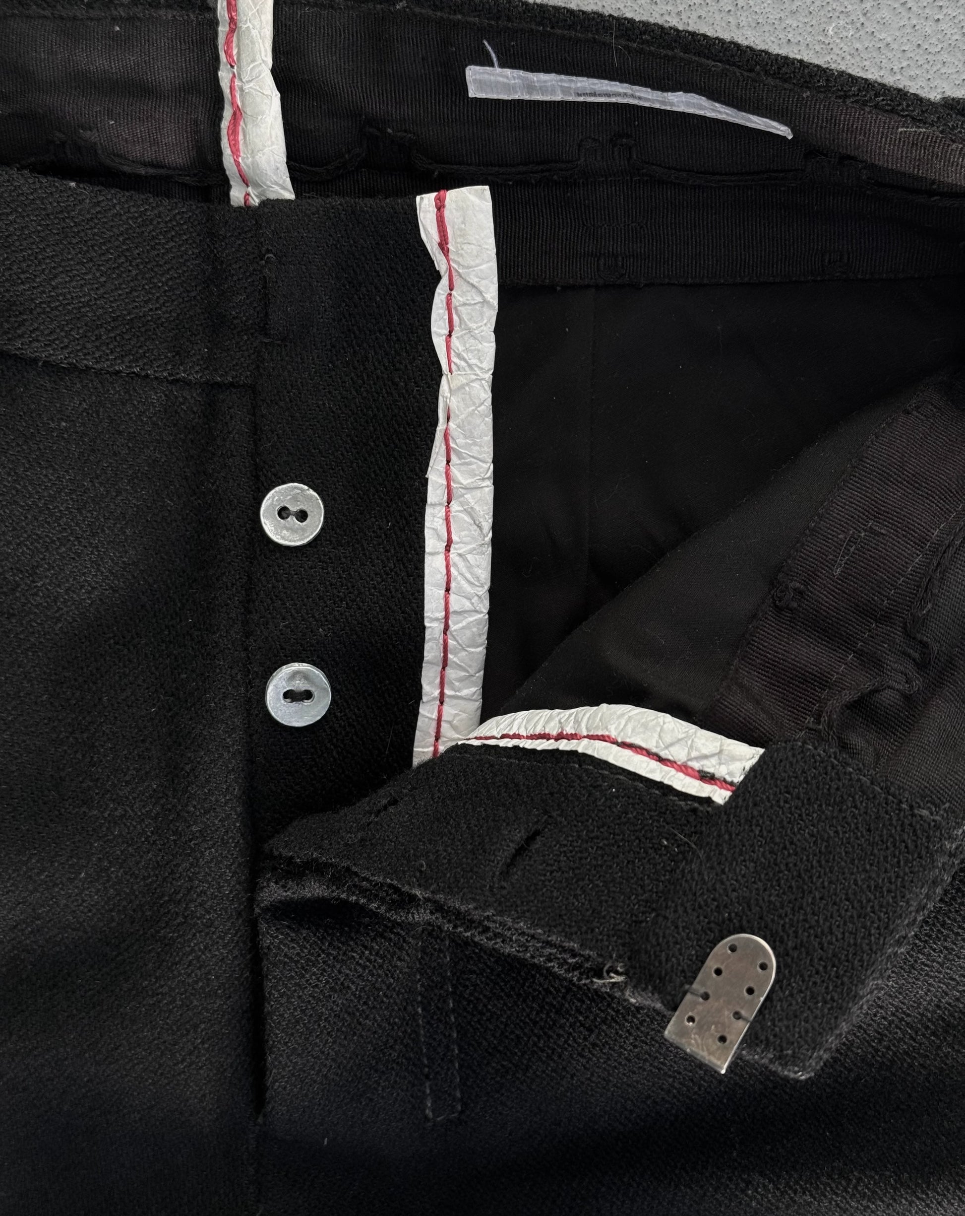 Close-up of a black shirt with white buttons and red stitching details.