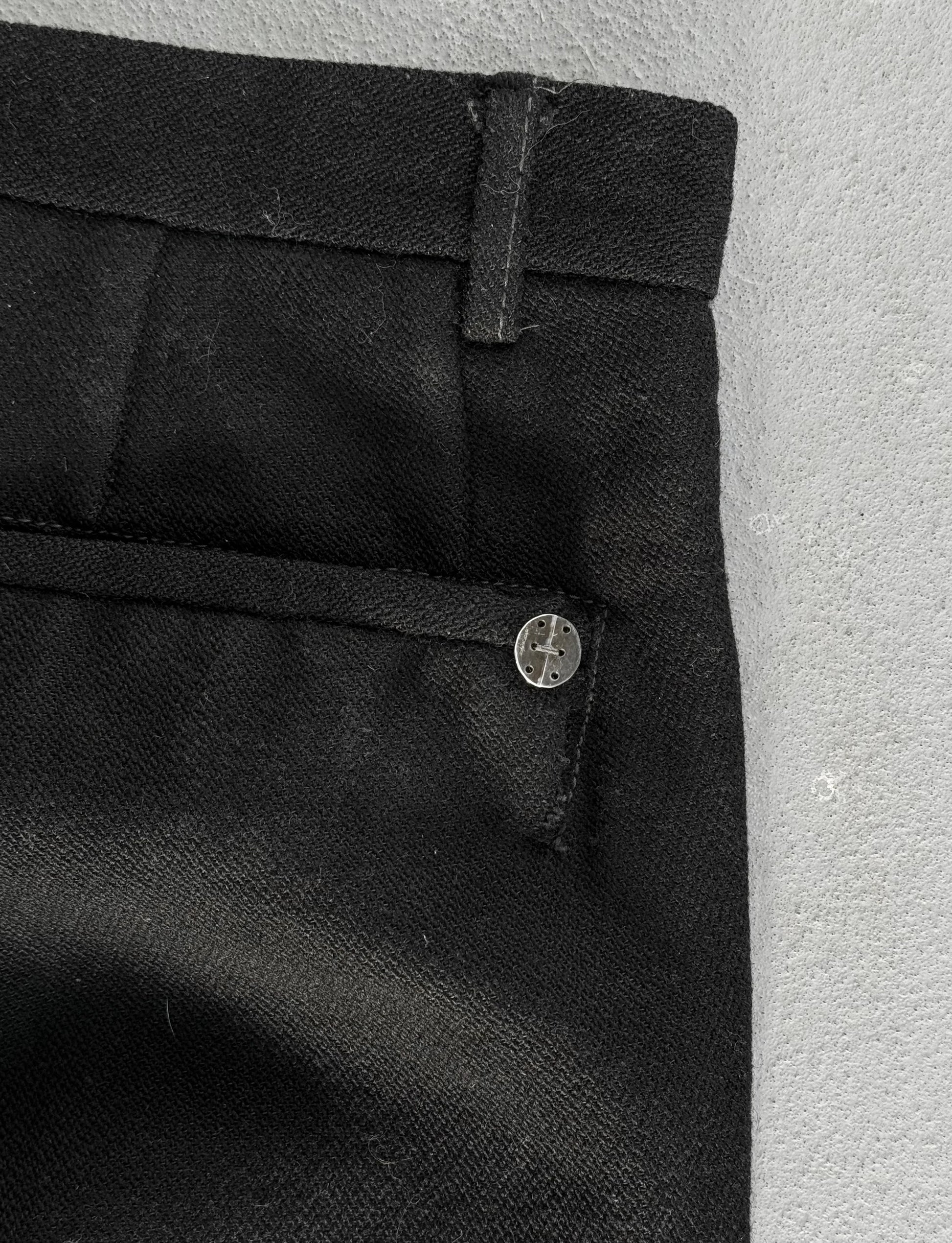 Close-up of black pants with a button on a light gray background