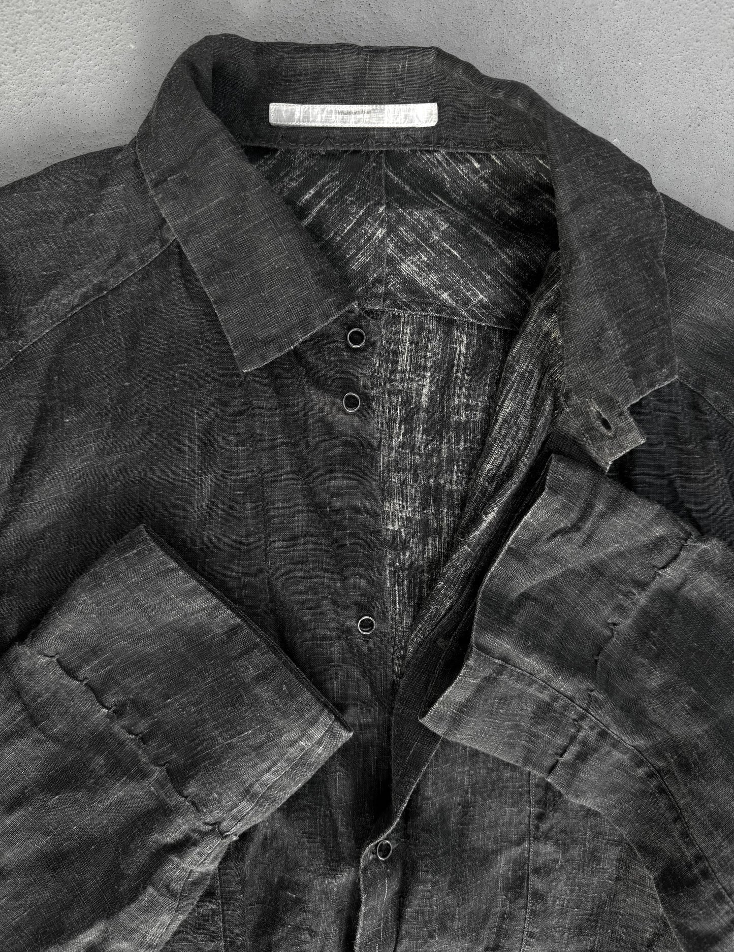 Dark denim shirt with a visible brand label on a gray background