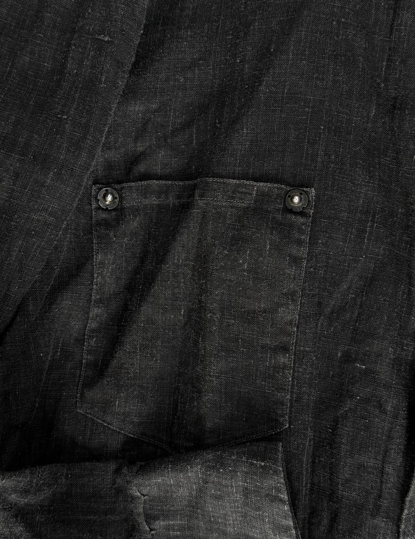 Close-up of a dark fabric pocket with buttons on a black background