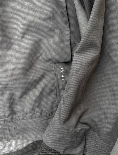 Close-up of a gray jacket with a brand logo on the chest pocket.