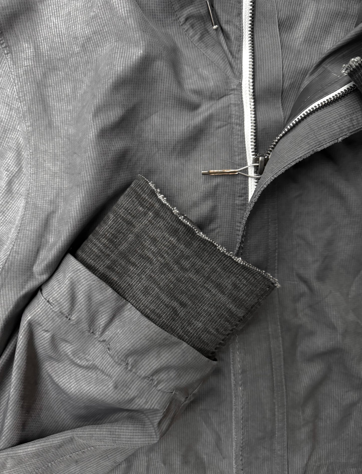 Close-up of a gray jacket with a zipper and patch detail