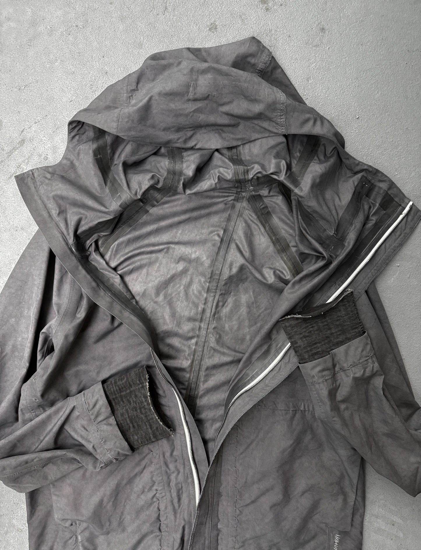 Dark gray raincoat with a hood on a light gray background