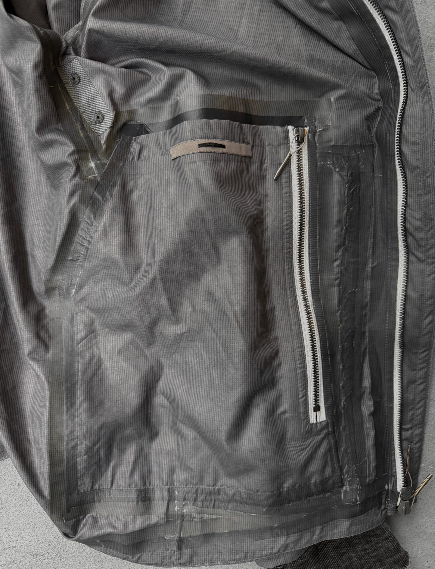 Close-up of a gray jacket with zippers and buttons on a neutral background