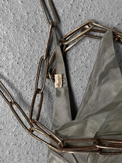 Bronze chainmaille bag with a lock on a textured gray background