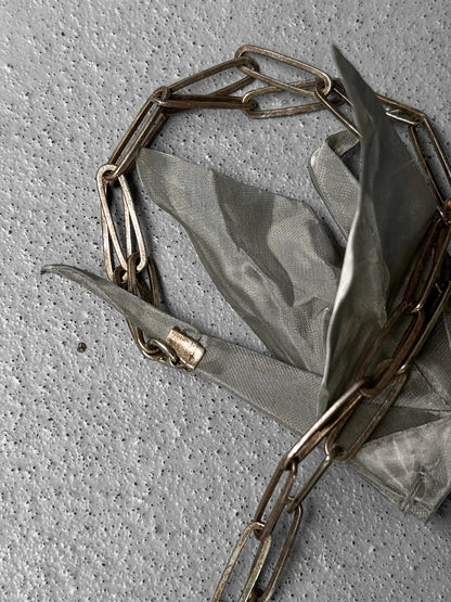 Gold chain necklace on a green fabric background