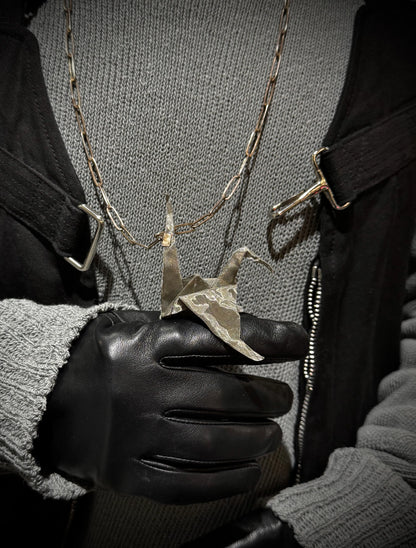 Person wearing a black glove holding a necklace with a unique pendant.