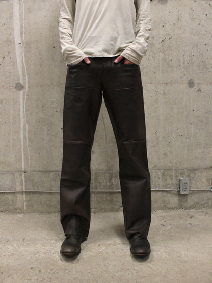 Person wearing black pants and a light gray long-sleeve shirt against a concrete wall.
