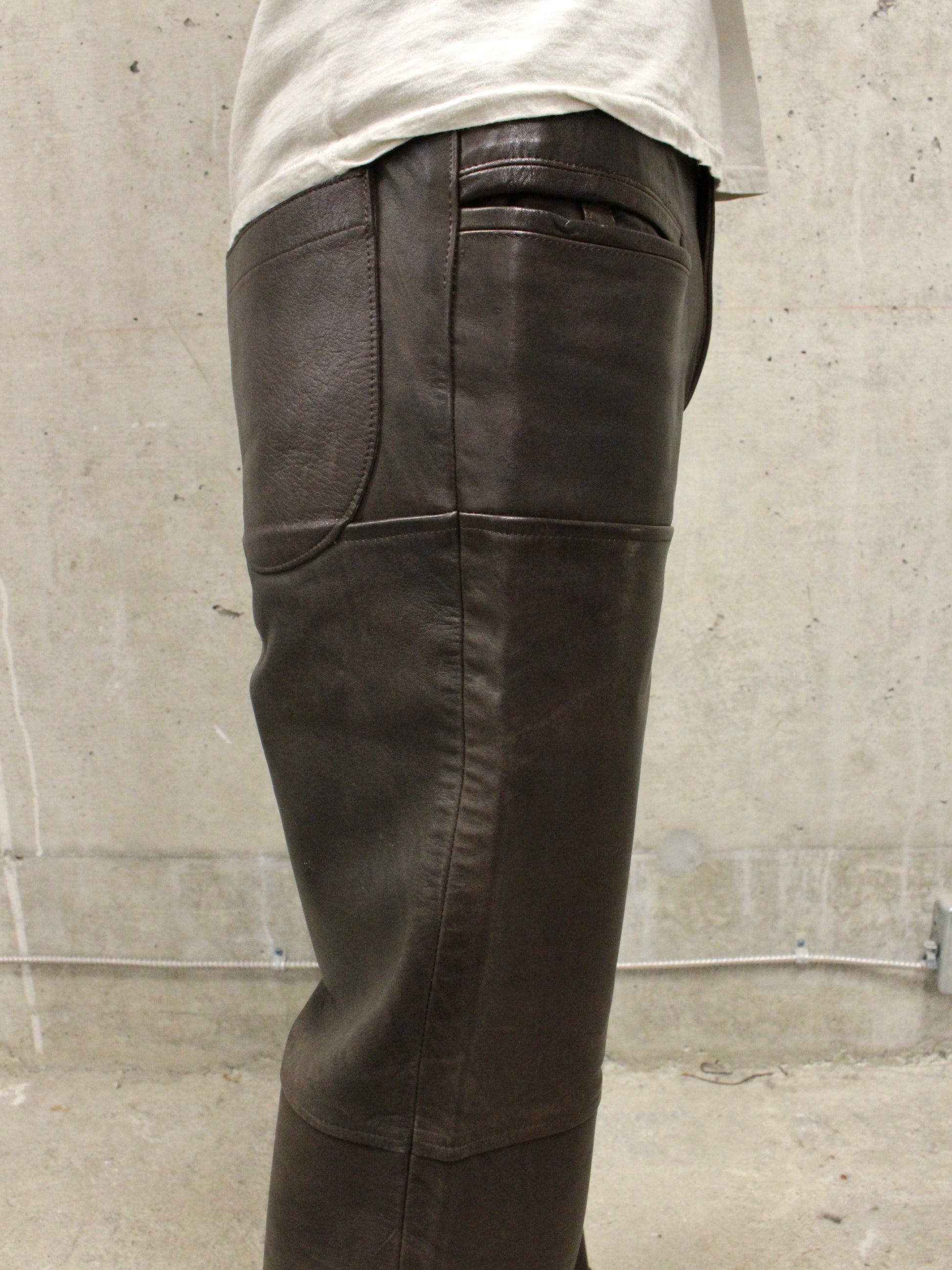 Dark leather pants worn by a person against a concrete wall.