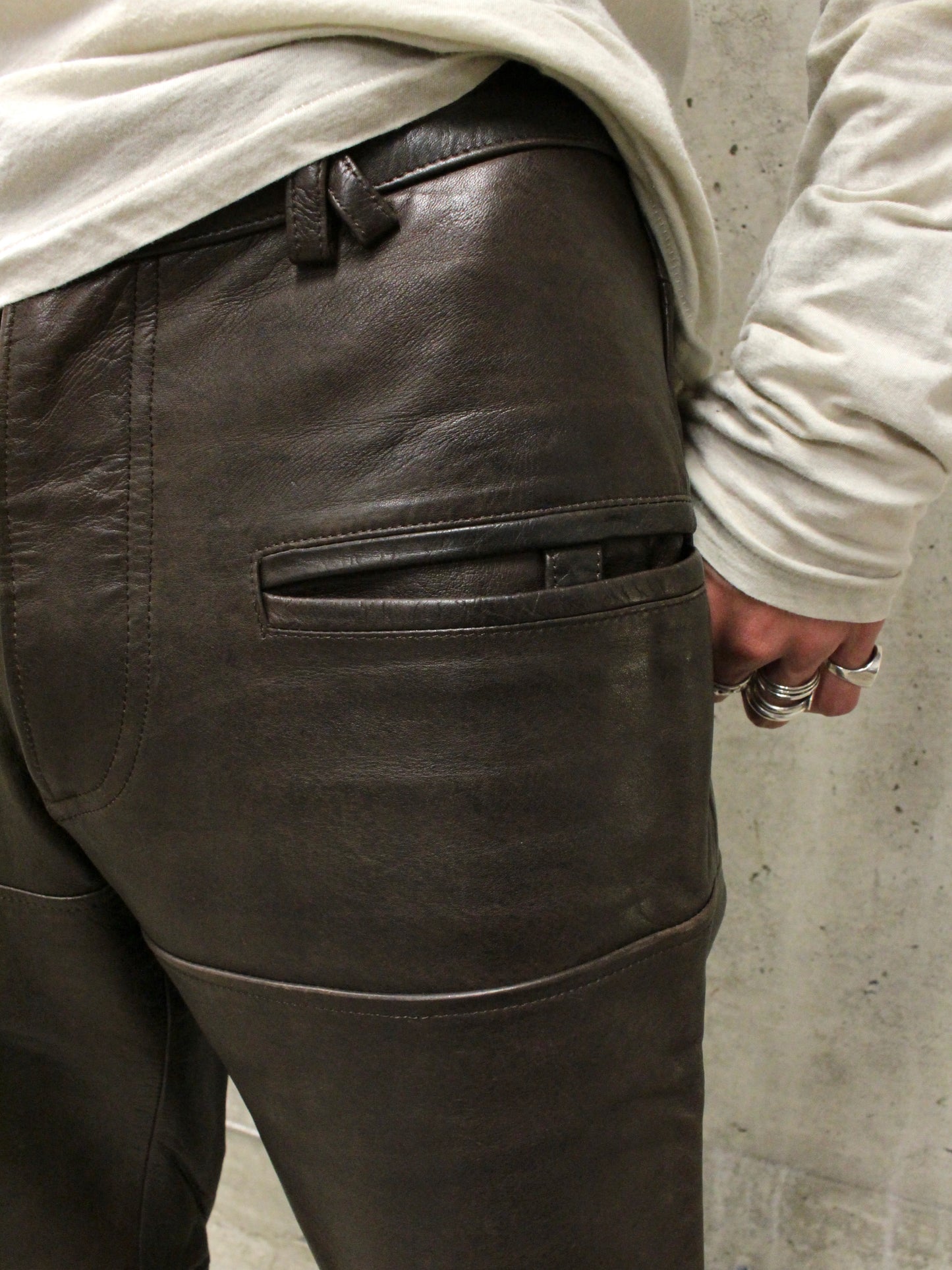 Dark leather pants worn by a person against a concrete wall.