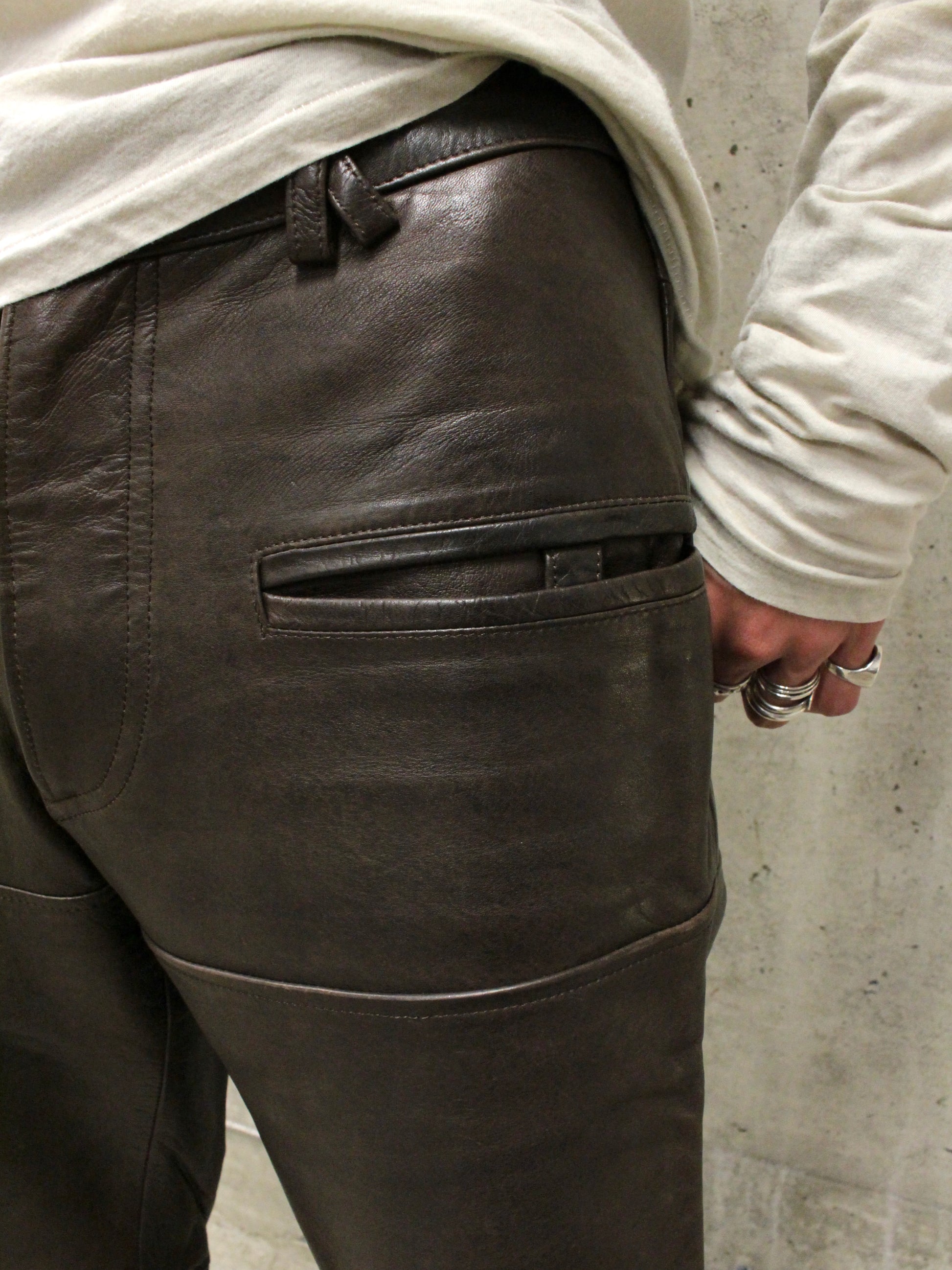 Dark leather pants worn by a person against a concrete wall.