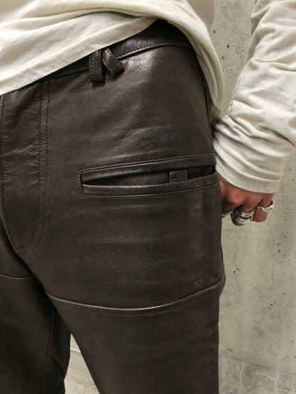 Dark leather pants worn by a person against a concrete wall.