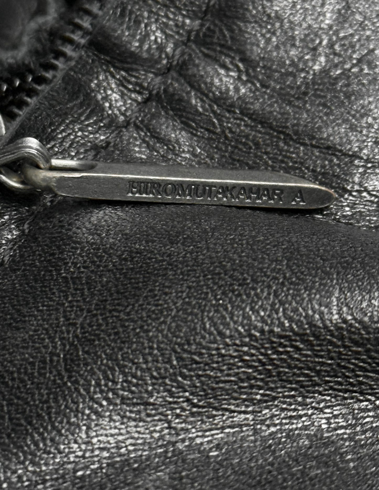 Close-up of a black leather bag with a metal tag.