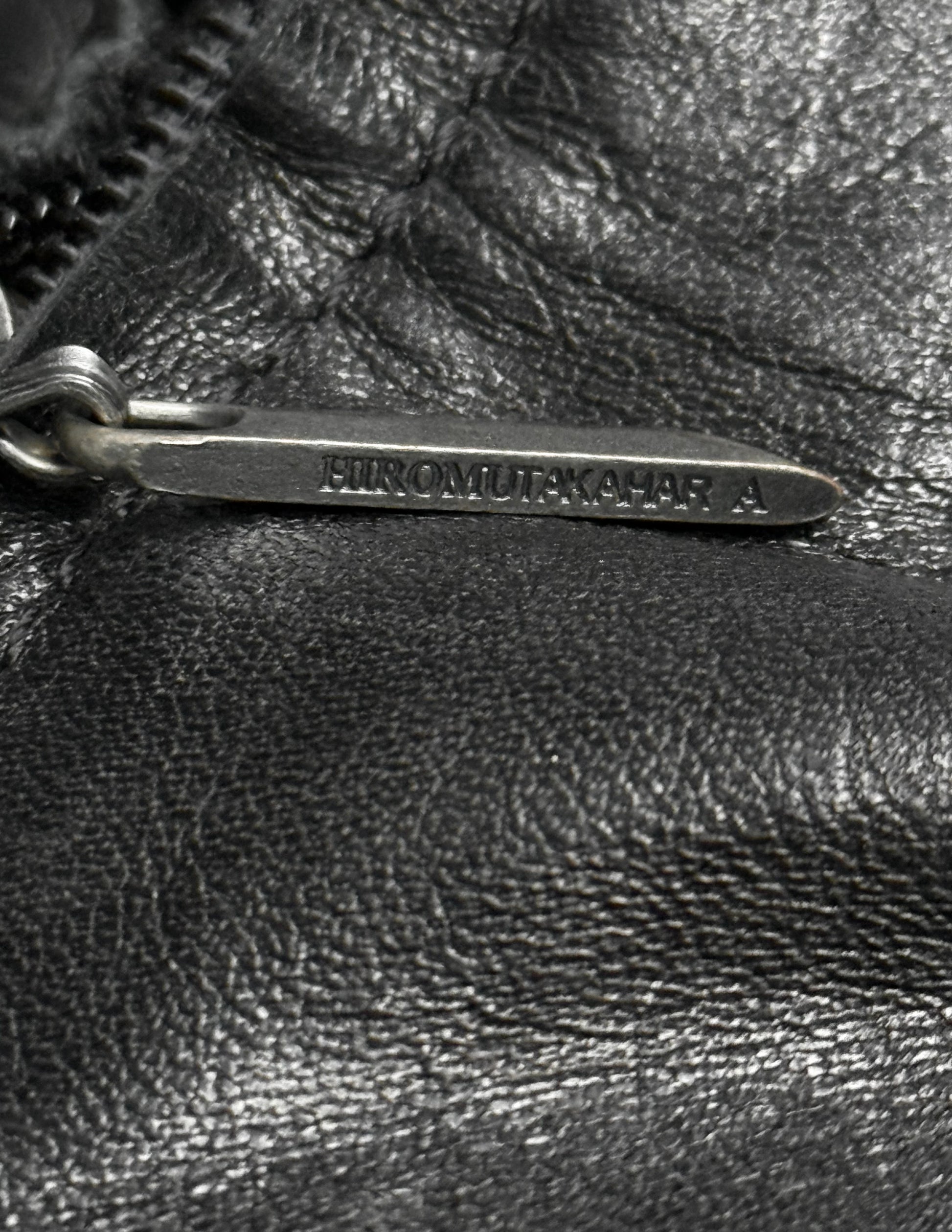 Close-up of a black leather bag with a metal tag.