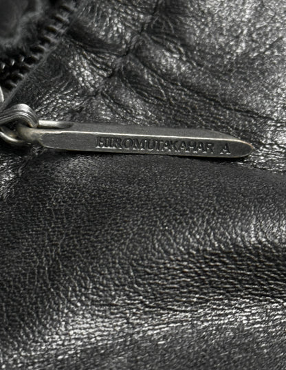 Close-up of a black leather bag with a metal tag.