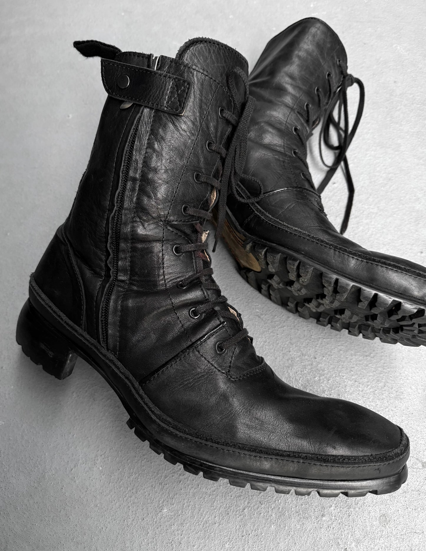 Pair of black leather boots on a light gray background