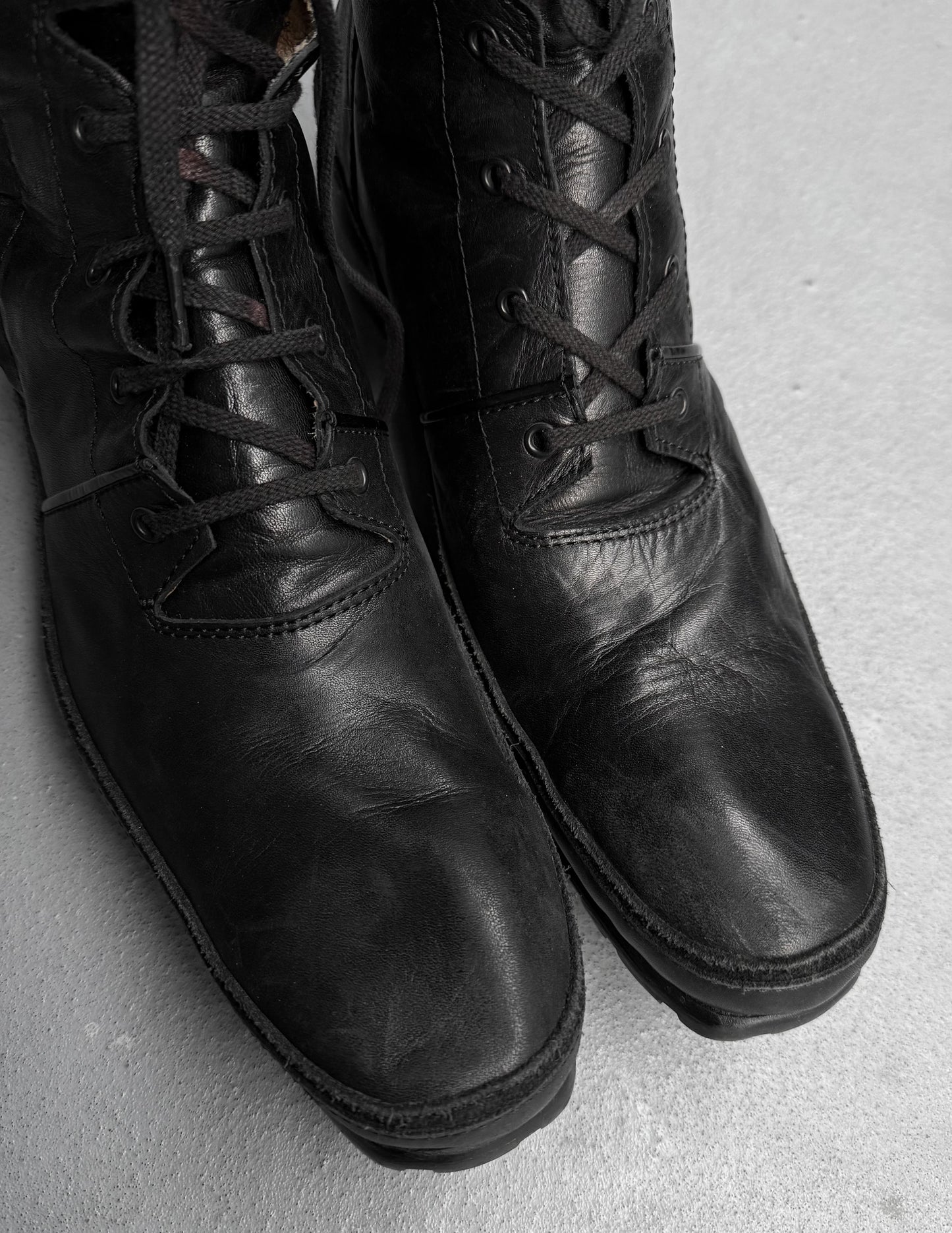 Pair of black leather boots on a light gray background