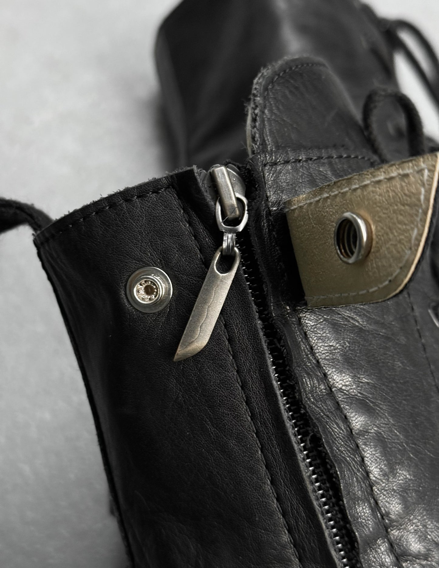Close-up of a black leather bag with a zipper and metal hardware.